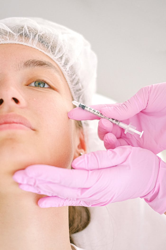 gallery-1 Close-up of a beautician administering facial injection treatment to a woman in a clinical setting.