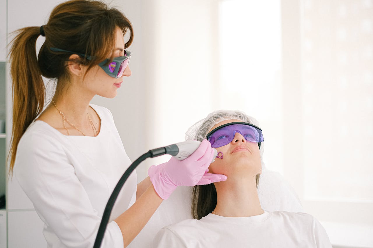 our-services-3 A cosmetologist performing laser treatment on a woman in a clinic setting.