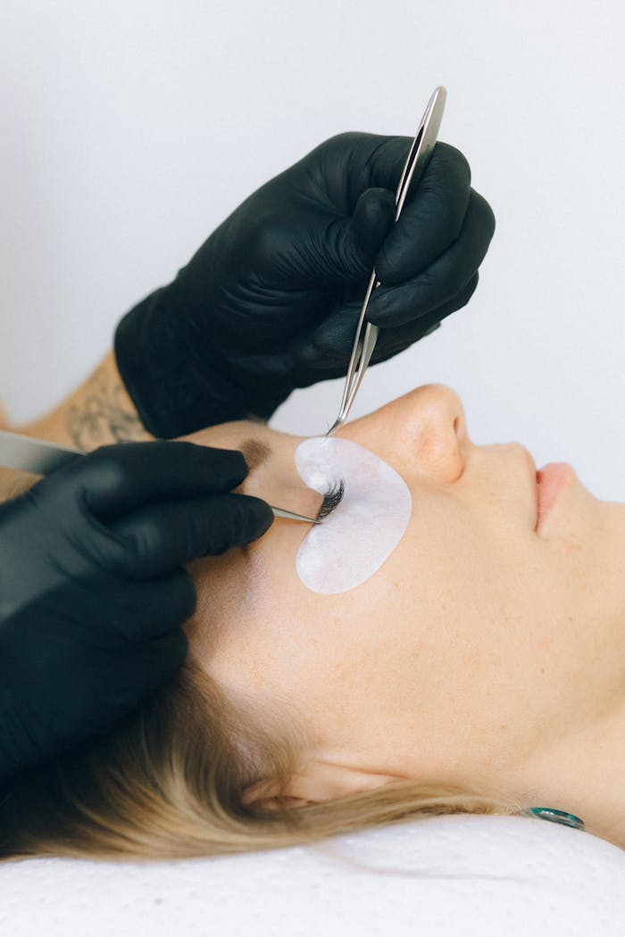 why-choose-us Close-up of a beautician applying eyelash extensions to a client in a salon setting.