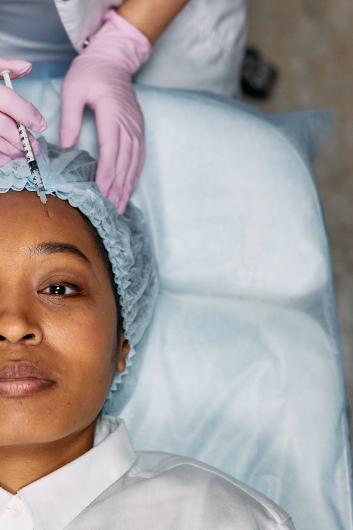 gallery-4 A woman receiving a cosmetic forehead injection in a clinical setting.