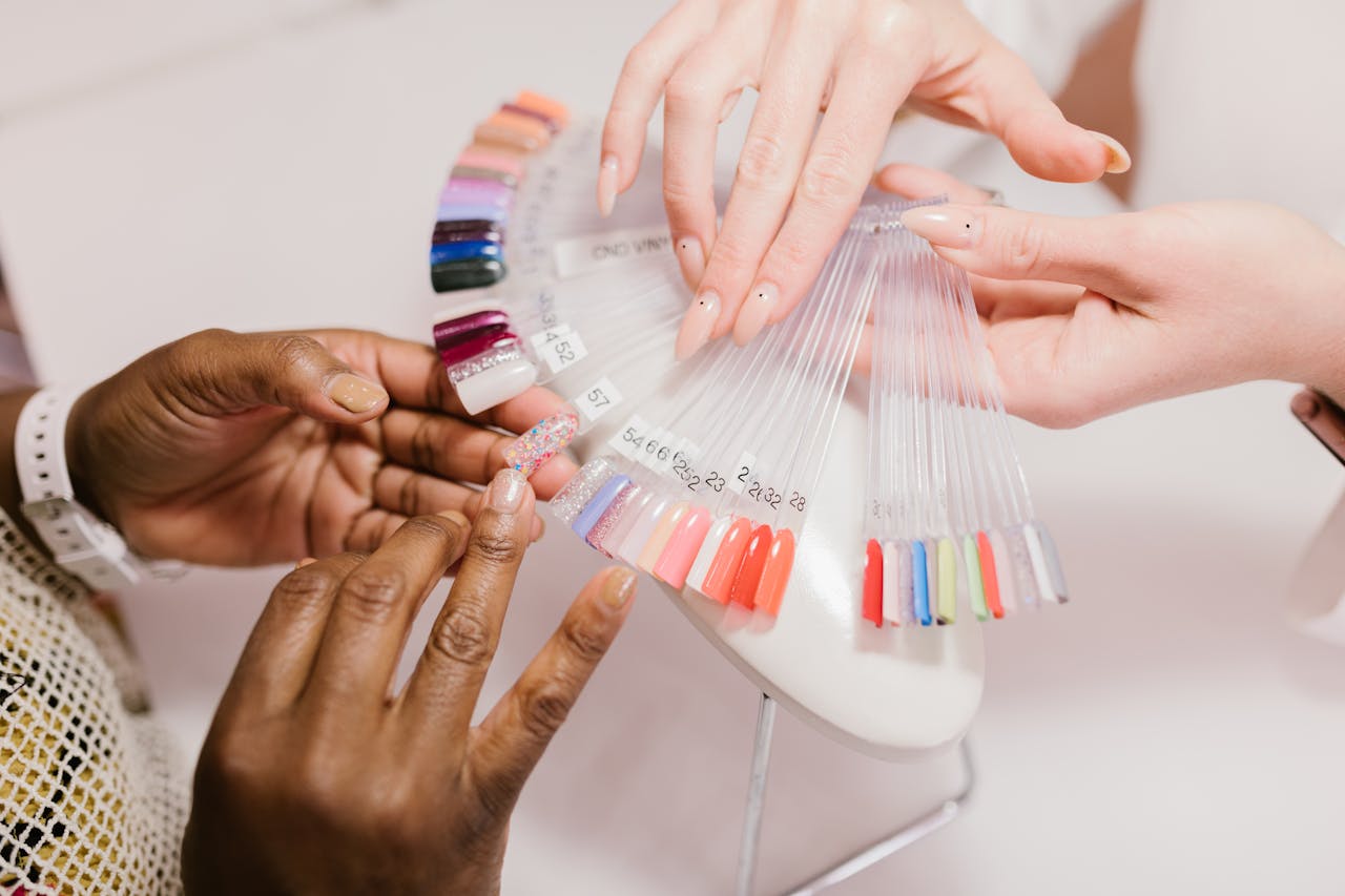 our-services-2 Close-up of hands choosing from a vibrant nail polish sample palette in a salon setting.